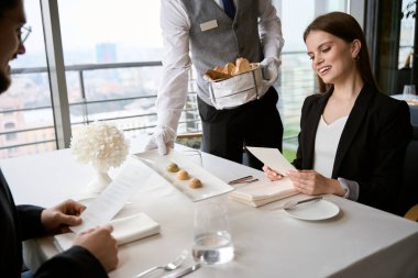 Garson, restoranda bir çift için masaya bir tabak abur cubur koyuyor, randevusu var, menüsünü tutuyor. Romantizm, tarih, ilişki kavramı