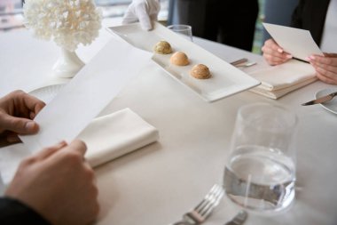 Garson lokantadaki insanlar için masaya bir tabak yemek koyuyor, kadın ve erkek menüyü ellerinde tutuyor. Romantizm, tarih, ilişki kavramı