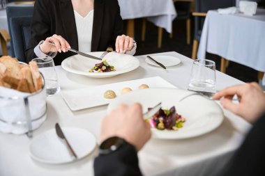 Çatal ve bıçak tutan ve randevu sırasında restoranda salata yemeye hazırlanan çift. Romantizm, tarih, ilişki kavramı