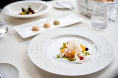 Sağlıklı salata, mango parçaları, burrata peyniri ve restorandaki beyaz tabakta otlar. Gurme hazırlığı, servis kavramı