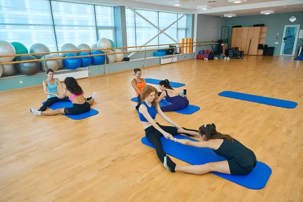 Sağlık grubundaki kadınlar esneme hareketleri yapıyor, kadınlar çorap egzersizleri yapıyor.