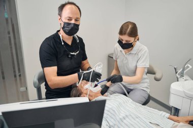 Klinikte çalışan bir grup dişçi koruyucu eldiven ve maske takıyor.