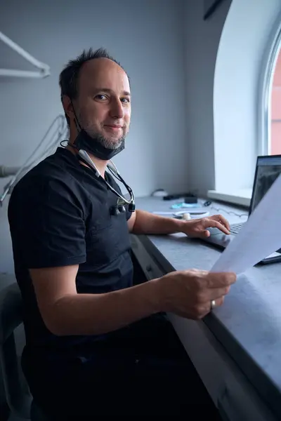 stock image Medic works on a laptop at his desk, studying work material