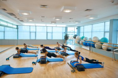 Kadınlar destek için özel platformlar kullanarak kalas egzersizi yapıyorlar.