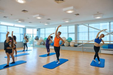 Bir grup kadın sırt kaslarını güçlendirmek için egzersiz yapıyor. Özel eğitim kıyafeti giymiş kadınlar.