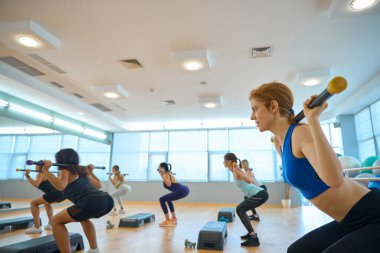 Platformlarda sopalarla etkili grup dersi, rahat spor ayakkabıları giyen kadınlar.