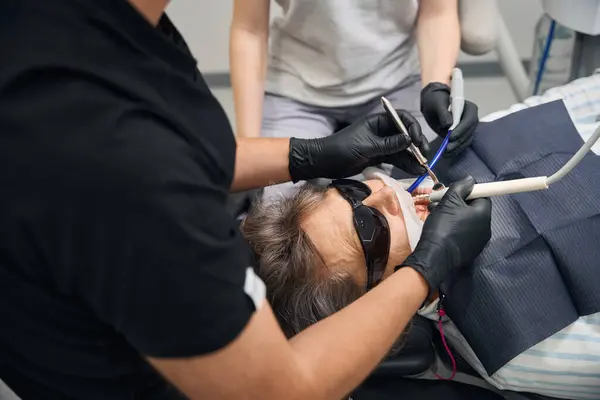 stock image Lady is getting her teeth treated at a dental clinic, the doctor is wearing protective gloves