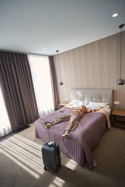 Otel odasına giriş yaptıktan sonra yaşlı bir kadının yatakta dinlenmesi. Seyahat odası.