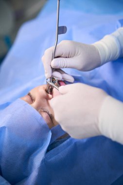Doktor modern bir klinikte tıbbi çelikten özel aletler kullanarak polipotomi yapıyor.