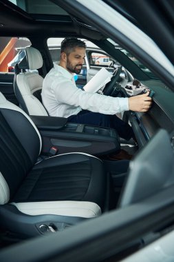 Gülümseyen iş adamı galeriden otomobil alırken yeni arabaları kontrol ediyor. Yeni araba sahibi kavramı