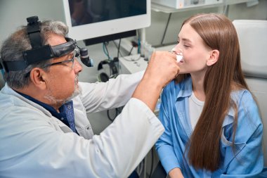 Doktorun hastaların gözlerine özen ve uzmanlıkla detaylı bir inceleme yaptığı yakın plan görüntüsü.
