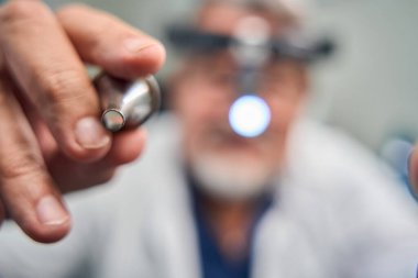 Doktorun elinde ışıklandırılmış bir inceleme aracıyla hassas göz bakımına odaklandığı detaylı bir fotoğraf.