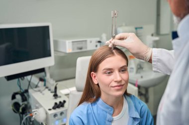 Doktor duyma yeteneğini ölçmek için diyapazon kullanırken hasta dikkatlice oturur.