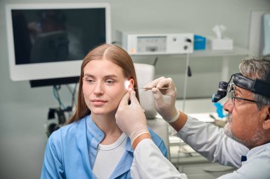 Hasta sakince oturur ve doktor özel aletlerle detaylı bir kulak muayenesi yapar.