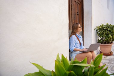 Guadalest İspanyol mahallesinde dizüstü bilgisayar kullanan genç bir kadın. Seyahat, mimari, yaşam tarzı konsepti