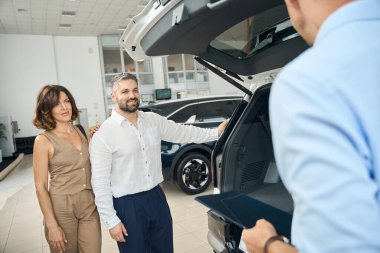 Galeride otomobil seçerken genç bir çift satıcıyla konuşuyor. Araba satışı, iş konsepti