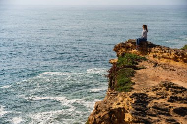 Genç bayan turist Portekiz 'deki Nazare okyanusunun panoramik manzarasının tadını çıkarıyor. Seyahat, manzara konsepti