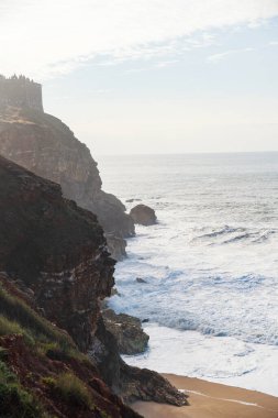 Portekiz, Nazare 'de kıyıya vuran turkuaz dalgaların olduğu güzel bir sahil manzarası. Seyahat, manzara konsepti