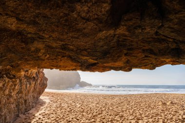 Portekiz, Nazare yakınlarında mağaraları ve sörf dalgaları olan plaj manzarası. Seyahat, manzara konsepti