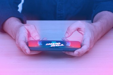 Hands playing game on smartphone. Man hand using mobile phone on wooden table.