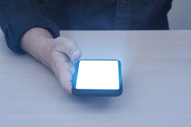 Glow lighting of phone in hands of guy. Close up of hand holding smart phone blank screen with glowing light effect.