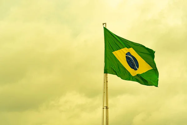 stock image Brazilian flag flying on an iron bar. National symbol. Pavilion. Symbol of the Federative Republic of Brazil. coat of arms. National identity. Green and yellow flag.