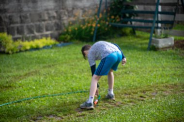 Brezilyalı çocuk bahçede su hortumuyla oynuyor..