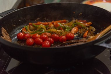 Biftek, soğanlı, domatesli ve biberli. Gaz ocağında kızartma tavasında hazırlanıyor.