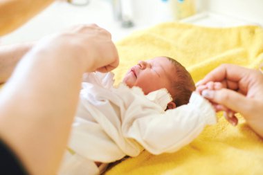Parents together dressing newborn baby after bath