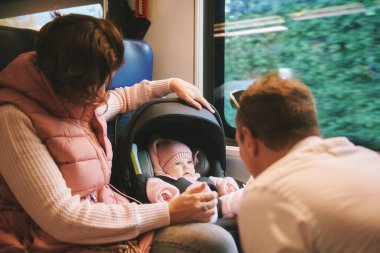 Genç mutlu ebeveynler küçük bebekle trenle seyahat ediyorlar. 