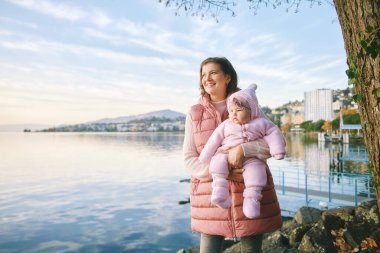 Mutlu bir anne ve güzel bir kızın açık hava portresi. Güzel bir kış gölü manzarası. Cenevre ya da Lac Leman, Montreux, İsviçre.