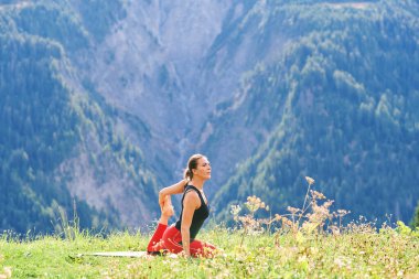 Dağlarda yoga yapan sağlıklı bir kadının açık hava portresi.