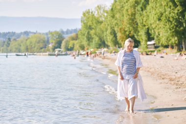 Açık havada, mutlu ve sağlıklı 50-55 yaşlarındaki olgun bir kadının göl veya deniz kenarında güneşli güzel bir günün tadını çıkaran portresi. Aktif yaşam tarzı, Preveranges, İsviçre 'de çekilmiş bir resim.