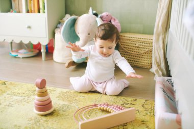 Evde eğitici oyuncaklarla oynayan 9 aylık sevimli bir kızın portresi.