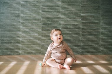  Oturma odasında yerde oturan sevimli bebeğin portresi.