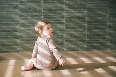  Oturma odasında yerde oturan sevimli bebeğin portresi.