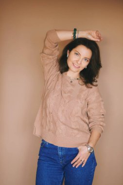 Bej arka planda poz veren 40 yaşında güzel bir kadının stüdyo portresi