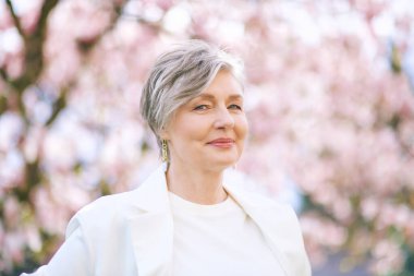 55-60 yaşındaki güzel bir kadının manolya ağacıyla poz verdiği bahar portresi.