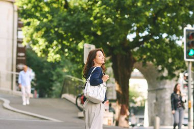 Sokaklarda poz veren mutlu olgun bir kadının açık hava portresi.