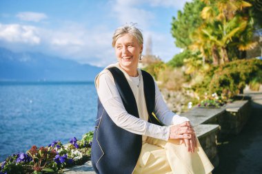 55-60 yaşlarında güzel bir kadının göl kenarında güneşli bir günün keyfini çıkarırken çekilmiş açık hava portresi, İsviçre Montreux 'da çekilmiştir.