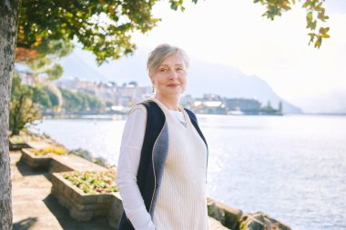 55-60 yaşlarında güzel bir kadının göl kenarında güneşli bir günün keyfini çıkarırken çekilmiş açık hava portresi, İsviçre Montreux 'da çekilmiştir.