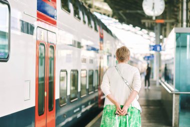 55 - 60 yaşındaki bir kadının tren istasyonundaki açık hava portresi. Tatil ve aktif yaşam tarzı.