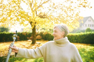Mutlu ve aktif yetişkin bir kadının açık hava portresi kendini telefon, sosyal medya ve vlog konseptiyle kaydediyor.
