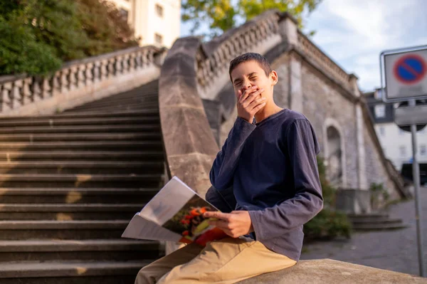 Zívající Teenager Sedí Betonových Schodech Balustrádu Otevřenou Učebnicí Rukou — Stock fotografie