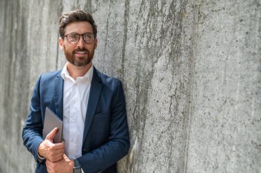 Dışarıdaki adam. Gözlüklü zarif bir genç adam duvarın yanında duruyor.