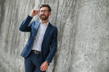 Dışarıdaki adam. Gözlüklü zarif bir genç adam duvarın yanında duruyor.