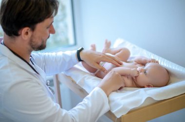 Kalp ritmi. Erkek çocuk doktoru steteskopla bebeğin kalbini dinliyor.