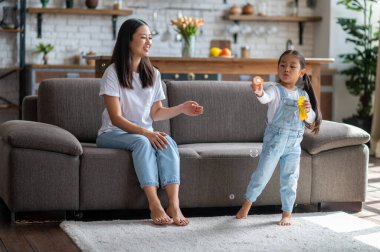 Gülümseyen mutlu anne kanepeye oturmuş tatlı çocuğunun değnekle kabarcıkları patlatmasını izliyor.