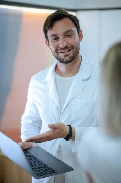 診察中にノートパソコンの画面に何かを見せる優しい医者を笑顔で — ストック写真
