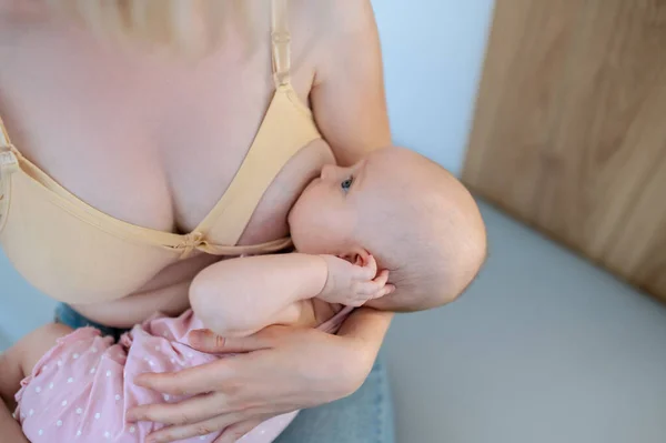 授乳中に彼女の新生児を抱いて部屋に座っている女性 — ストック写真
